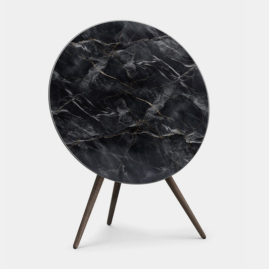 Bang & Olufsen BeoPlay A9 and BeoSound A9 cover replacement featuring Noir Marquina black marble pattern with gold veining, printed on acoustically transparent fabric, wooden tripod stand, angled product view on white background