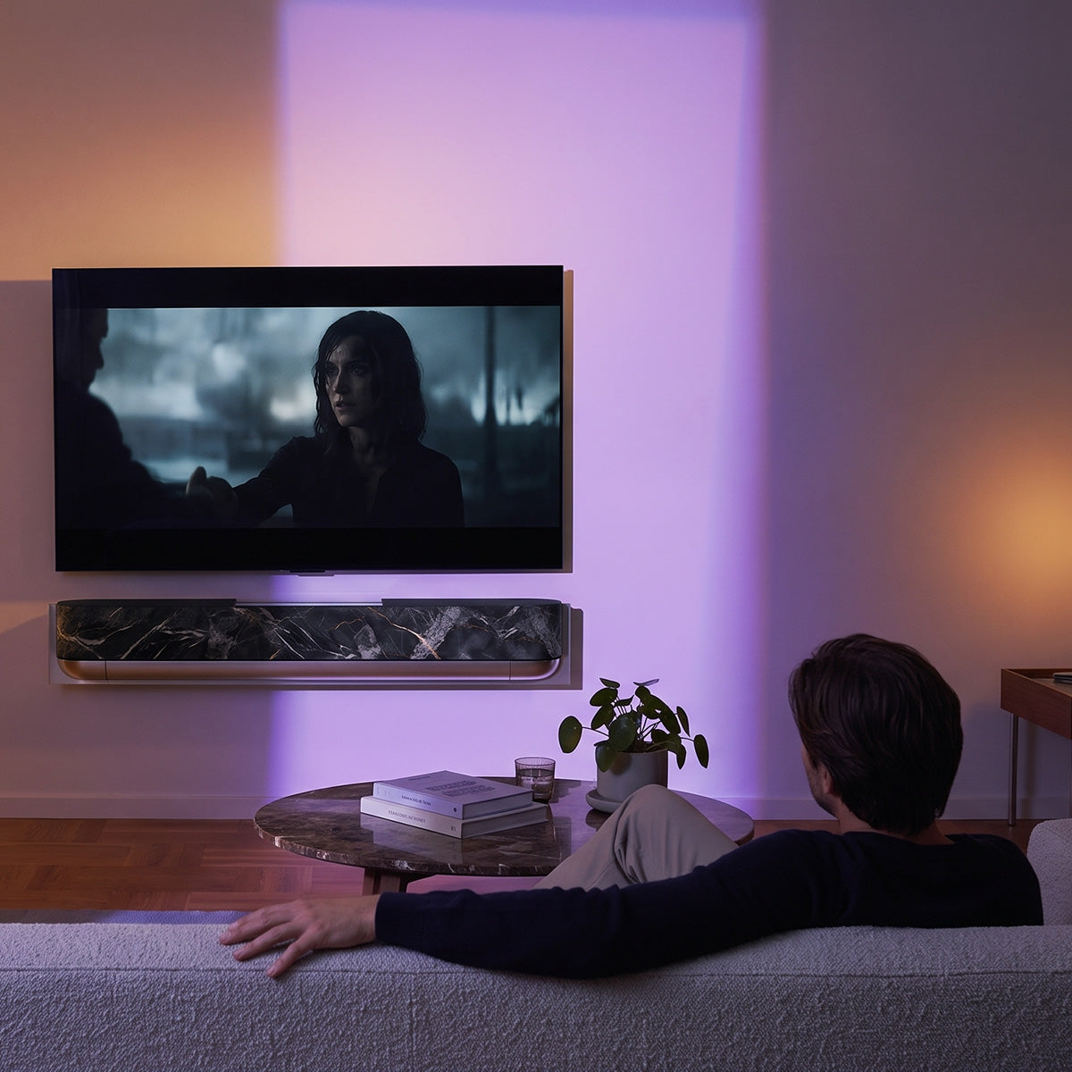 Bang & Olufsen BeoSound Theatre skin in Noir Marquina black marble design with gold veining mounted below wall TV in moody living room with ambient purple lighting