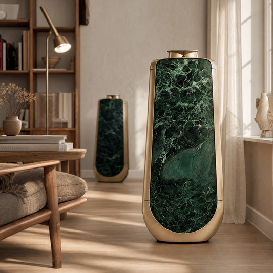 Bang & Olufsen BeoLab 50 in Verde St. Denis green marble skins, styling a living room with a grey modular sofa and wood-panelled wall