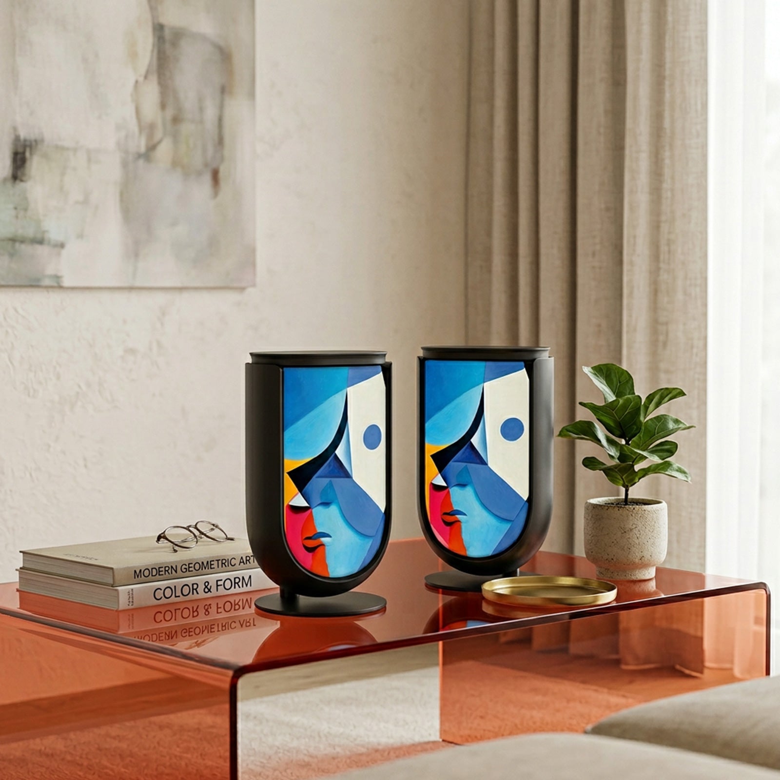Bang & Olufsen BeoLab 8 speaker covers Éclat — Cubist Portrait by Tegrino Studio in a carefully styled living area, featuring cubist abstract face in vivid blue, yellow and pink geometric planes on stereo pair atop amber glass table beside art books and fiddle leaf fig plant