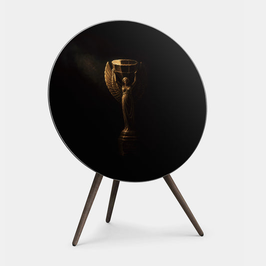 Bang & Olufsen BeoPlay A9 and BeoSound A9 speaker cover replacement Nike by Tegrino Studio featuring golden winged victory goddess sculpture on deep black background with dramatic chiaroscuro lighting, printed on acoustically transparent fabric
