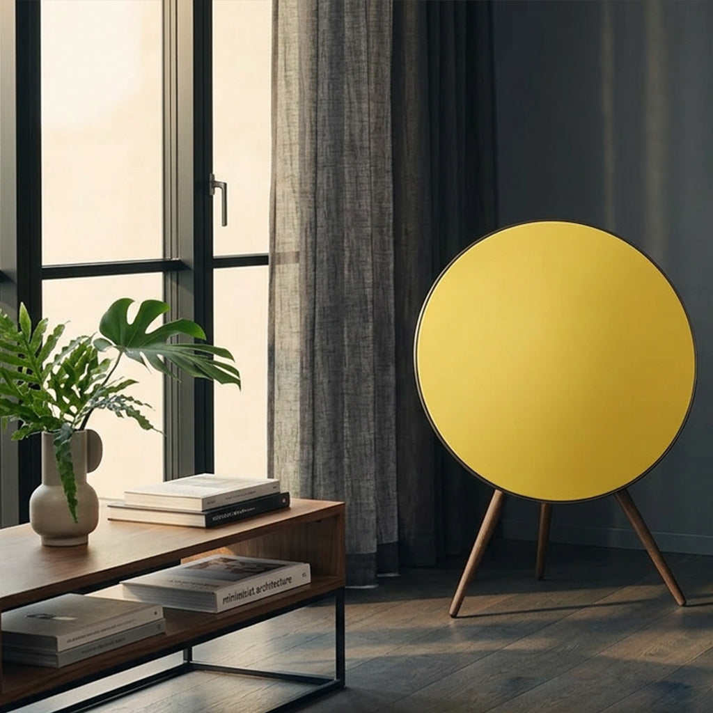 Bang & Olufsen BeoPlay A9 and BeoSound A9 speaker cover Solid Colors by Tegrino Studio in a contemporary living space, featuring warm yellow solid surface against dark grey wall with monstera plant and architecture books