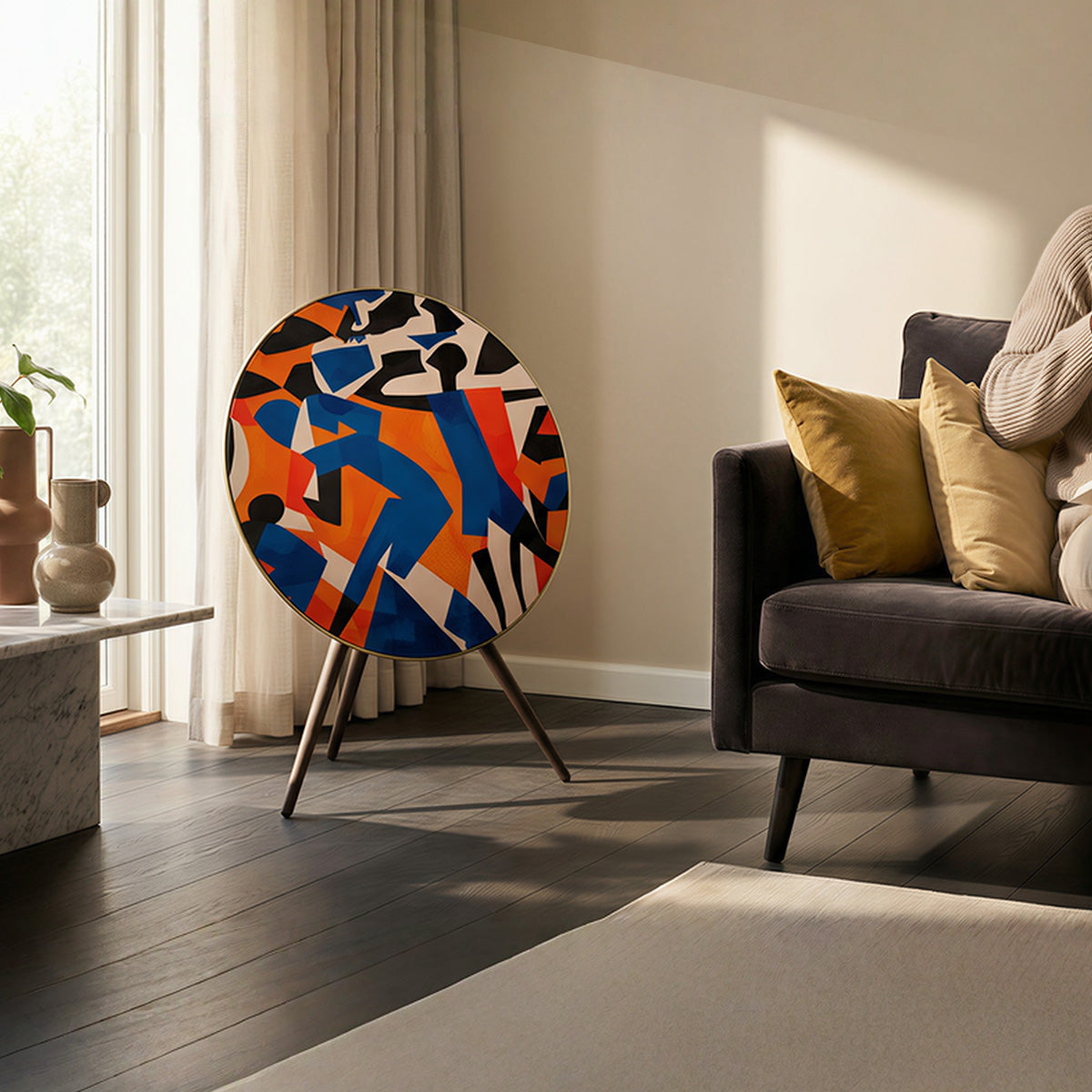 Bang & Olufsen BeoPlay A9 and BeoSound A9 speaker skin Verve by Tegrino Studio in a contemporary living space, showcasing bold figurative silhouettes in vivid blue, orange and red beside a dark sofa with mustard cushions on dark hardwood floor