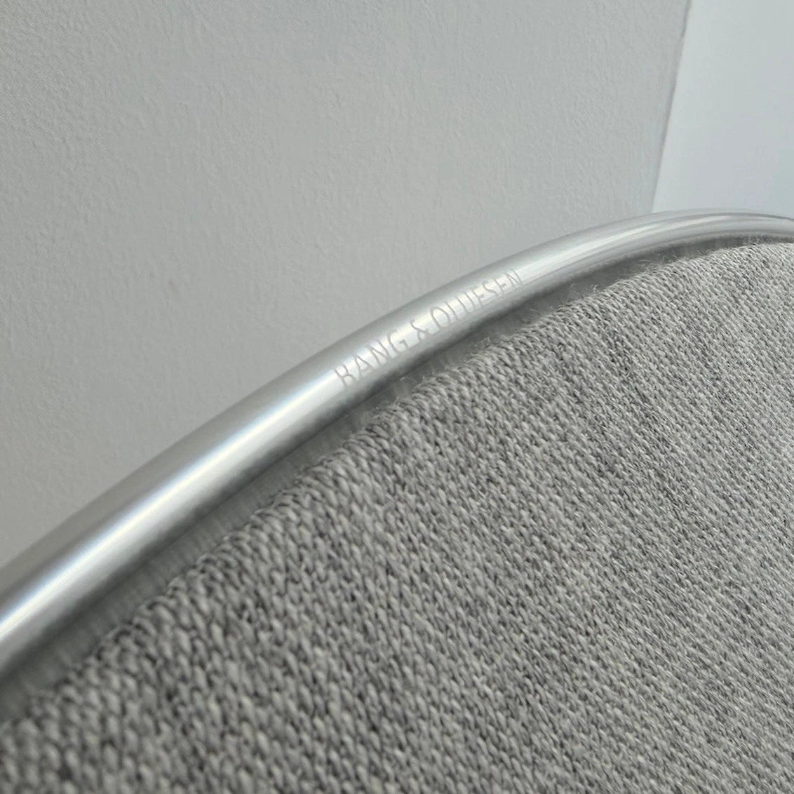 Bang & Olufsen BeoPlay A9 and BeoSound A9 Kvadrat cover Natural by Bang & Olufsen close-up detail showing natural grey wool blend textile texture and engraved Bang & Olufsen aluminium ring