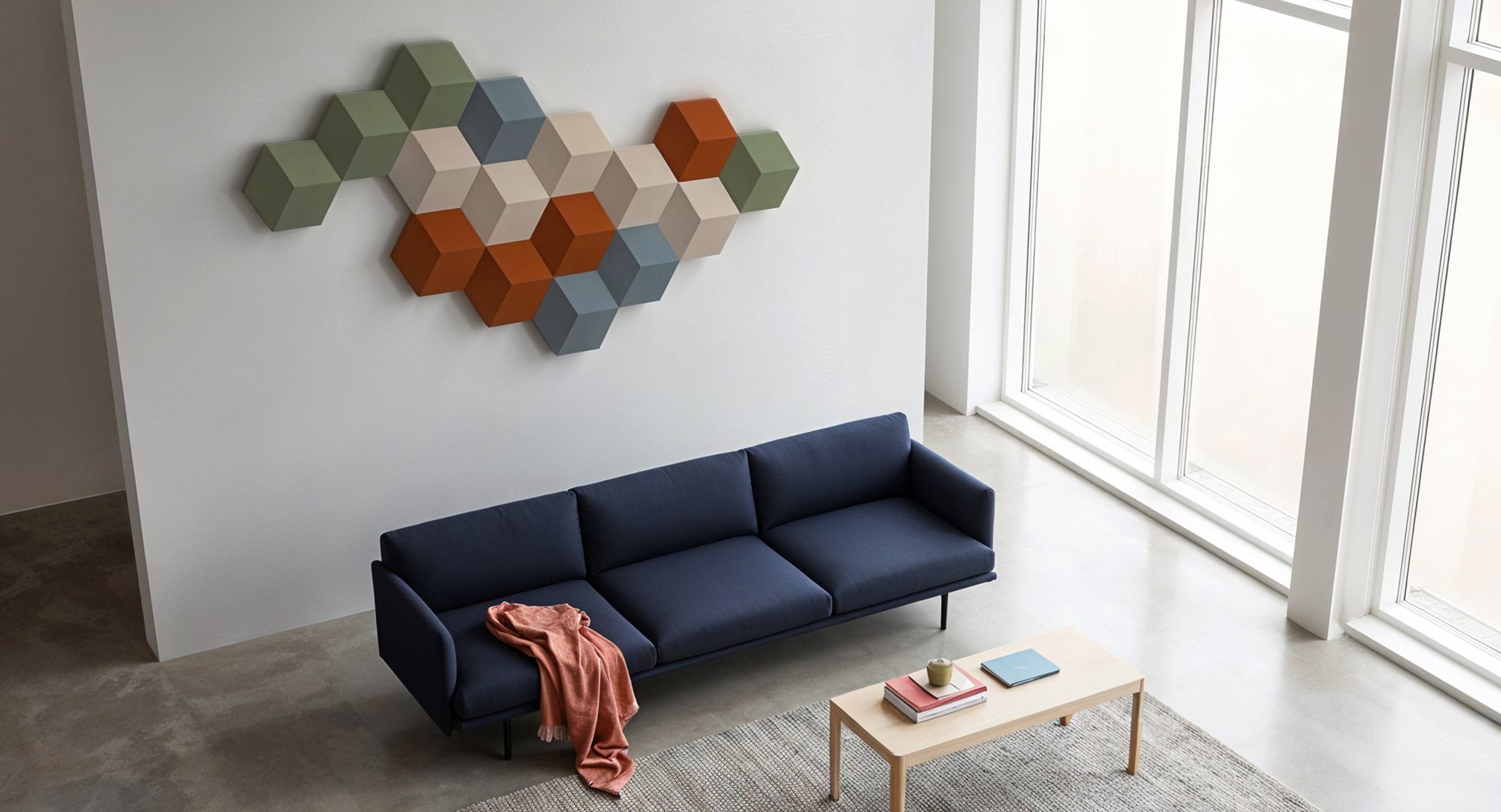 Bang & Olufsen BeoSound Shape speaker cover solid colour collection by Tegrino Studio featuring mixed hexagonal tiles in sage green, warm beige, burnt orange and slate blue installed on white wall above a navy sofa