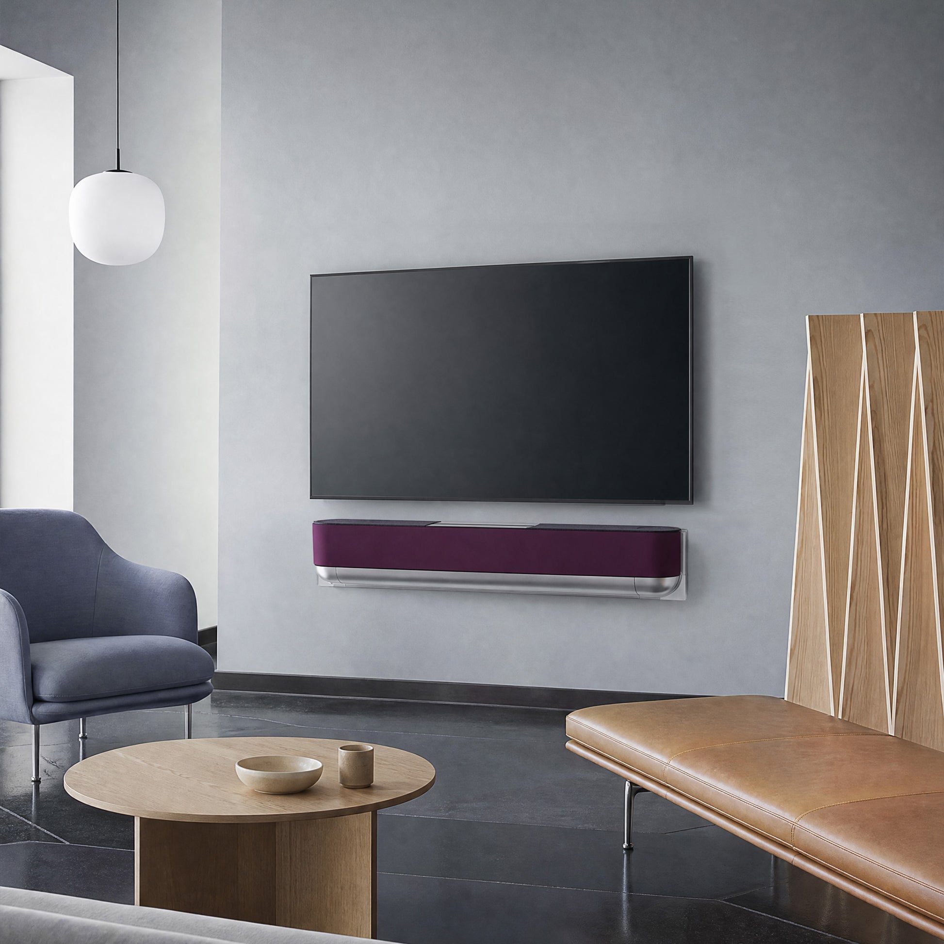 Bang & Olufsen Beosound Theatre with the Damson cover by Tegrino Studio beneath a wall-mounted screen, beside a navy armchair