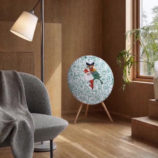 Spot the Santa cover by Tegrino Studio on a Bang & Olufsen Beosound A9 in a wood-panelled living room, a child chasing a ball of green yarn