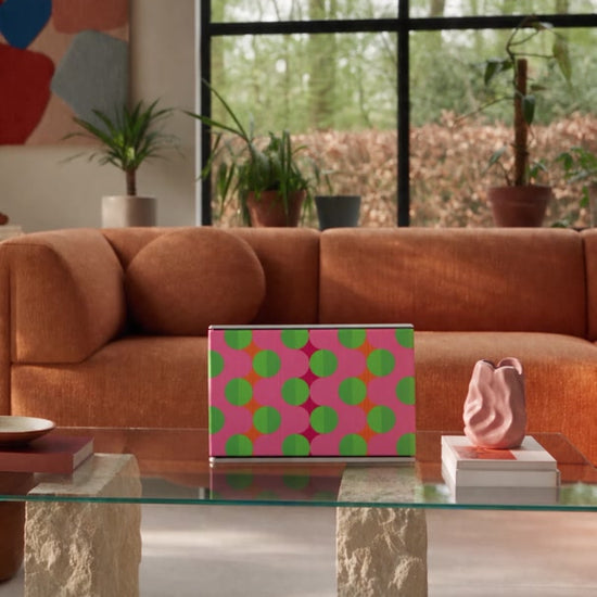 Summer Beat cover by Tegrino Studio on a Bang & Olufsen Beosound Level on a glass coffee table in a sunlit living room with an orange sofa
