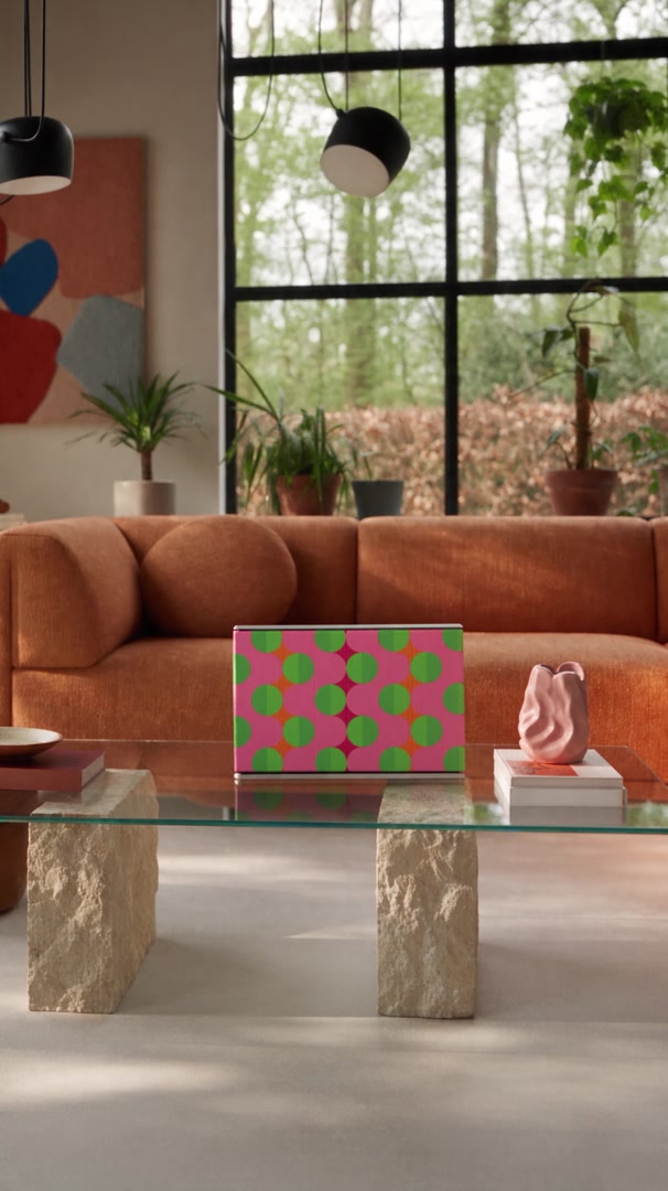 Summer Beat cover by Tegrino Studio on a Bang & Olufsen Beosound Level on a glass coffee table in a sunlit living room with an orange sofa